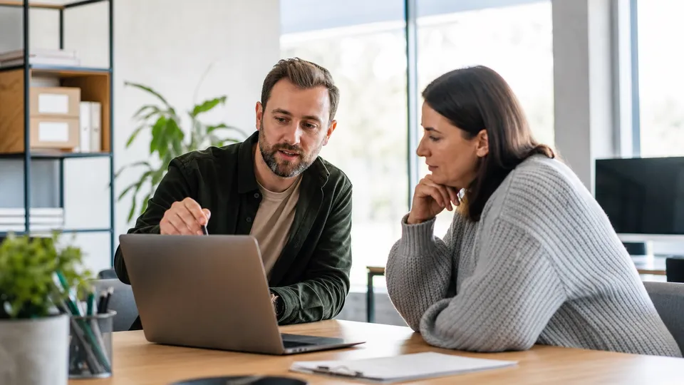 A friendly IT support conversation over a laptop in a bright office